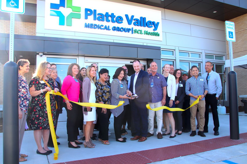 Platte Valley Medical Group Practice Manager Barb Trujillo and SCL Front Range Vice President of Operations Boris Kalikstein hold the scissors to cut the bright yellow ribbon on the practice's new Brighton location on Aug. 23.